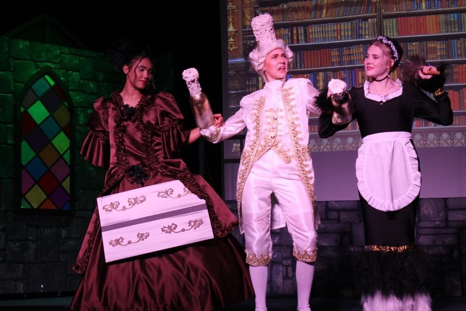 Three performers in costume with the enchanted cake